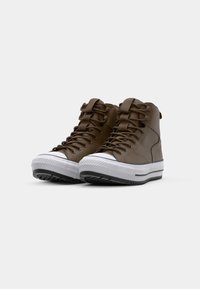 Brown high-top sneakers with a smooth finish, rubber white toe cap, black and white striped sole, and matching brown laces.