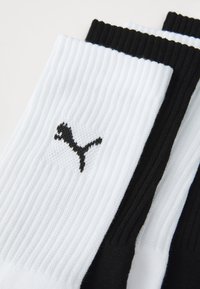 Kolm paari spordisokke valge ja musta värviga, ribakujulise tekstuuriga ja väikese musta Puma logoga küljes.