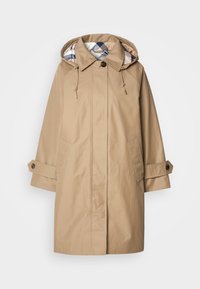 Beige Regenmantel mit Kapuze, mit gefüttertem Innenfutter im Karomuster, geknöpften Ärmelbündchen und Vordertaschen. Hergestellt aus wasserabweisendem Stoff.