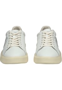 Weiße Ledersneaker mit beigen Gummisohlen, flaches Schnürdesign, glatte Textur und einem Logo-Detail an der Seite.