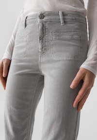 Grau Cordhosen mit glatter Textur, ausgestattet mit frontalen Taschen, einer einzelnen Gesäßtasche und einer taillierten Passform.