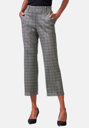 Woman wearing gray plaid cropped trousers with front pockets and black heels, standing against a white background.