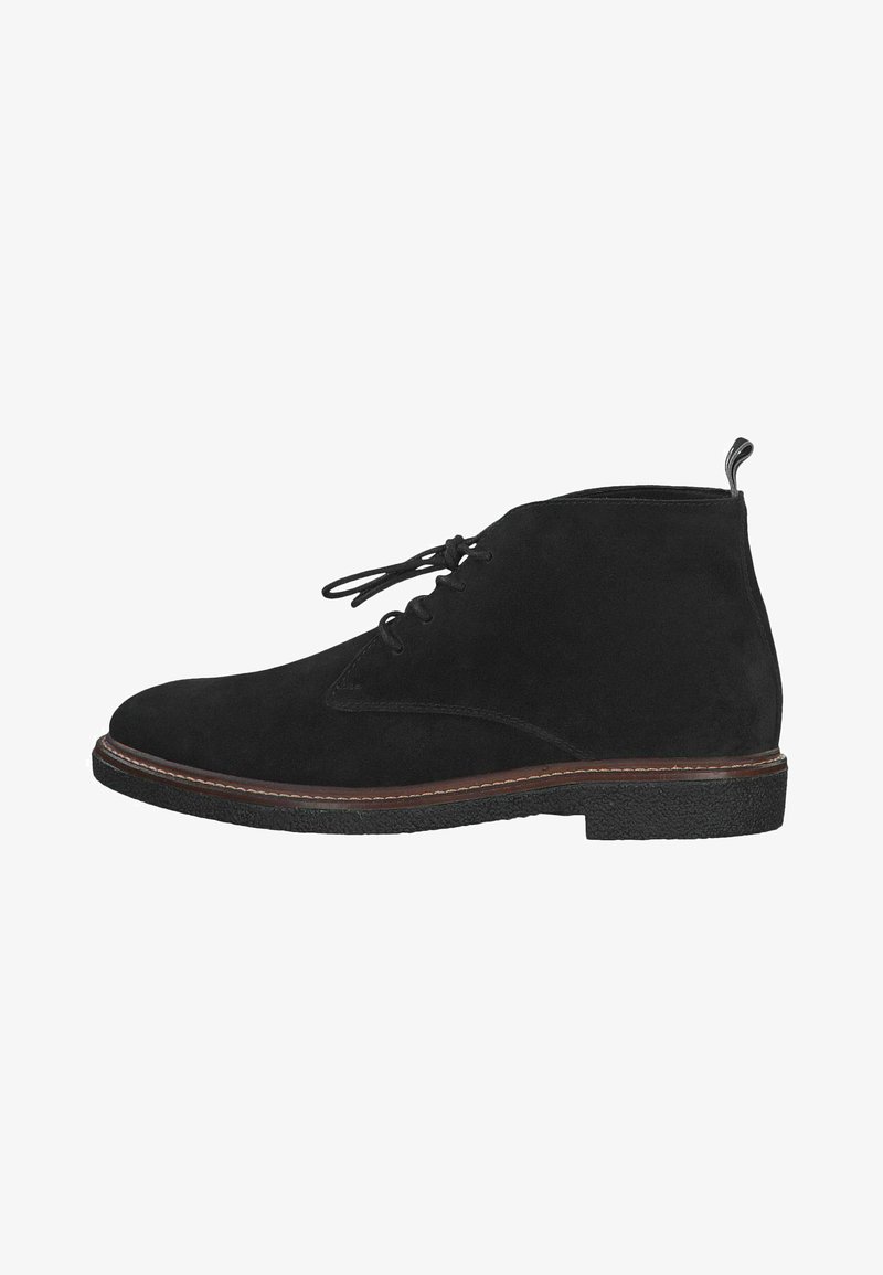 Botas de tornozelo em camurça preta com bico arredondado, atacadores na frente e uma sola de borracha contrastante com costura. Apresenta uma aba na parte de trás do calcanhar.