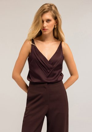 Camiseta de satén burdeos con escote en V profundo y pliegues diagonales, combinada con pantalones sueltos a juego. Textura suave, diseño minimalista.