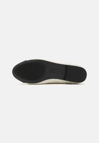 Talpa de pantof cu cauciuc negru texturat și partea superioară din material țesut de culoare crem. Prezintă un design plat, marcaj discret și vârf rotund.