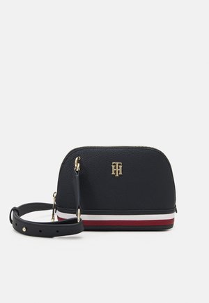 Lille sort læder crossbody taske med justerbar rem, gyldent logo og vandrette røde, hvide og marineblå striber ved bunden.