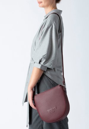 Bordeaux læder crossbody taske med struktureret overflade, lynlåslukning og justerbar rem. Har præget logo på fronten.