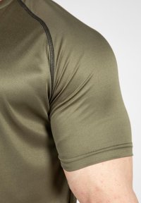 Olijfgroen, aansluitend sportshirt met een gladde textuur, korte mouwen en contrasterende zwarte stiksels langs de naden.