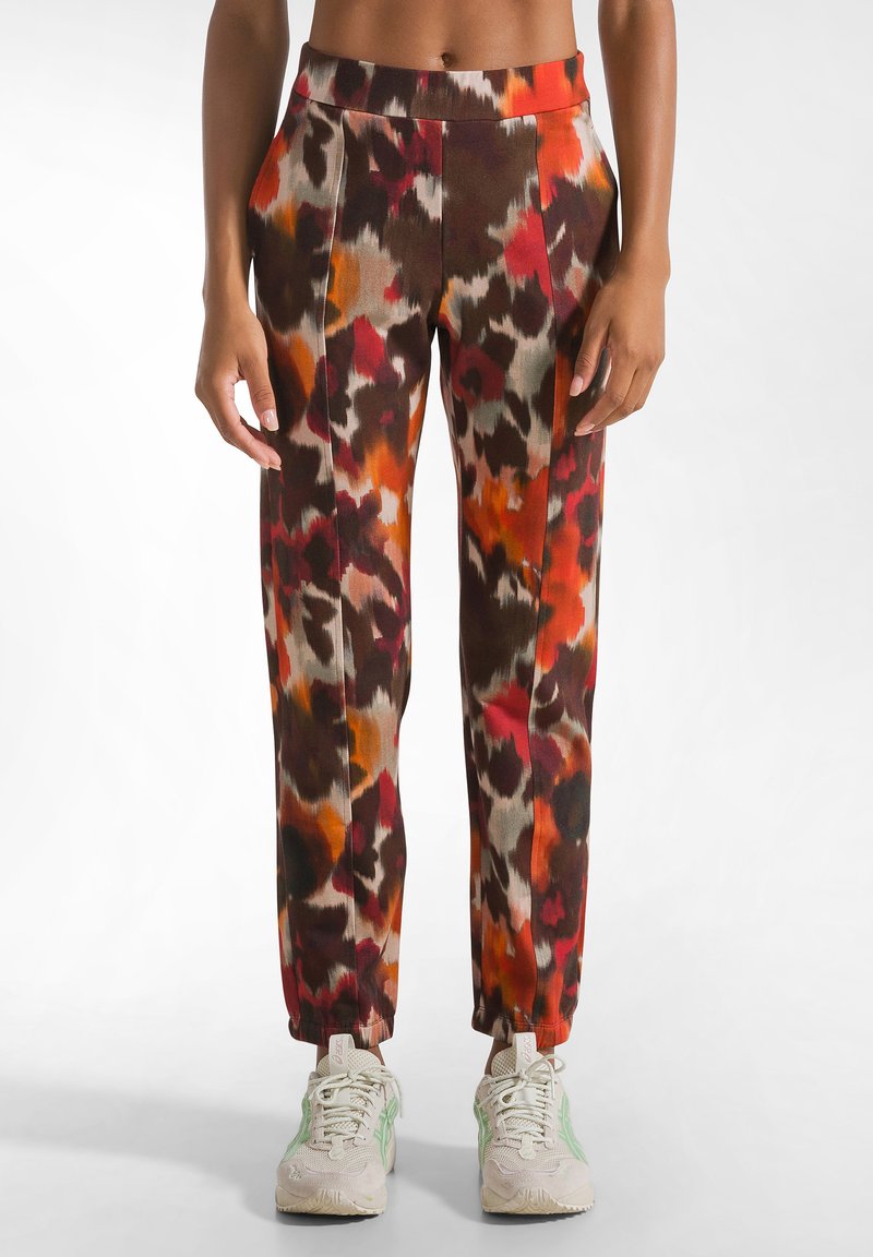 Kleurige, geblokte broek met tinten bruin, oranje en rood. De stof heeft een gladde textuur, met een elastische tailleband en taps toelopende manchetten.