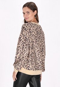 Hanorac cu imprimeu leopard în nuan�țe de bej și negru, cu croială lejeră, mâneci lungi și manșete și tiv de o nuanță deschisă. Purtați cu colanți negri.