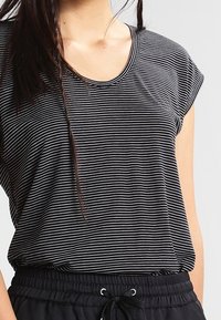 Svart och vit randig t-shirt med korta ärmar och rundad halsringning, gjord av mjukt tyg, i kombination med lösa svarta shorts med elastisk midja.