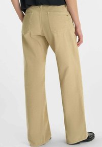 Brede beige corduroy broek met zichtbare achterzakken, textuurstof en een lichte verticale ribbeling op het oppervlak.