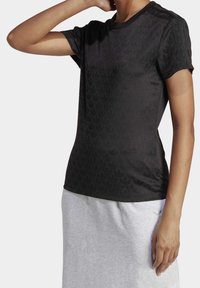 Svart idrottströja med subtilt mönstrad textur, rund halsringning och tre horisontella ränder på axlarna. Standard passform.