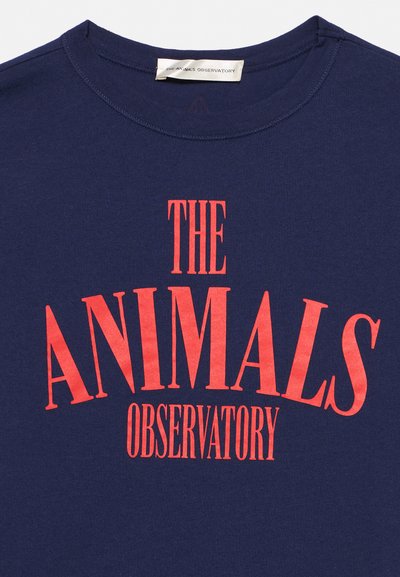 Тъмносиня риза с червен текст "THE ANIMALS OBSERVATORY" отпред и малък бял етикет вътре в яката.