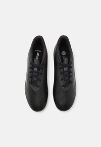 Scarpe sportive nere con una tomaia sintetica testurizzata, dotate di un design con lacci e fori per la ventilazione. Stile minimalista.