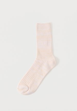 Chaussette côtelée jaune clair avec une texture douce, d'une longueur mi-mollet et dotée d'un renfort au niveau des orteils et du talon pour plus de durabilité.