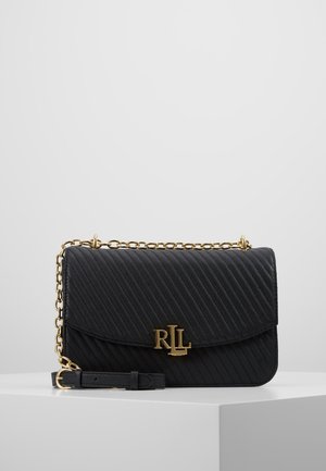 Sac à main en cuir matelassé noir avec bandoulière chaîne dorée et fermoir logo RLL doré, exposé sur un socle blanc sur fond gris clair.