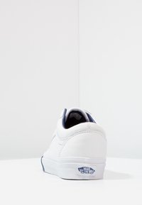 Sneaker in pelle bianca con interno blu, caratterizzata da punta tonda, dettagli cuciti e logo Vans sul tallone.