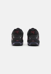 Zapatillas deportivas negras que combinan materiales de malla y sintéticos. Destacan los acentos rojos y la amortiguación en el talón; cuellito acolchado para mayor comodidad.