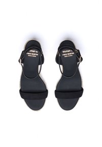 Zwarte sandalen met een suède-achtige bovenkant, verstelbare strap en een jute-omhulde zool. Eenvoudig design, platte voetbed en minimale hardware-details.