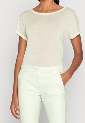 Světlounce zelené tričko s krátkými rukávy, kulatým výstřihem a ohrnutými okraji rukávů, v kombinaci se světlounce zelenými kalhotami na míru. Měkká, texturovaná látka.