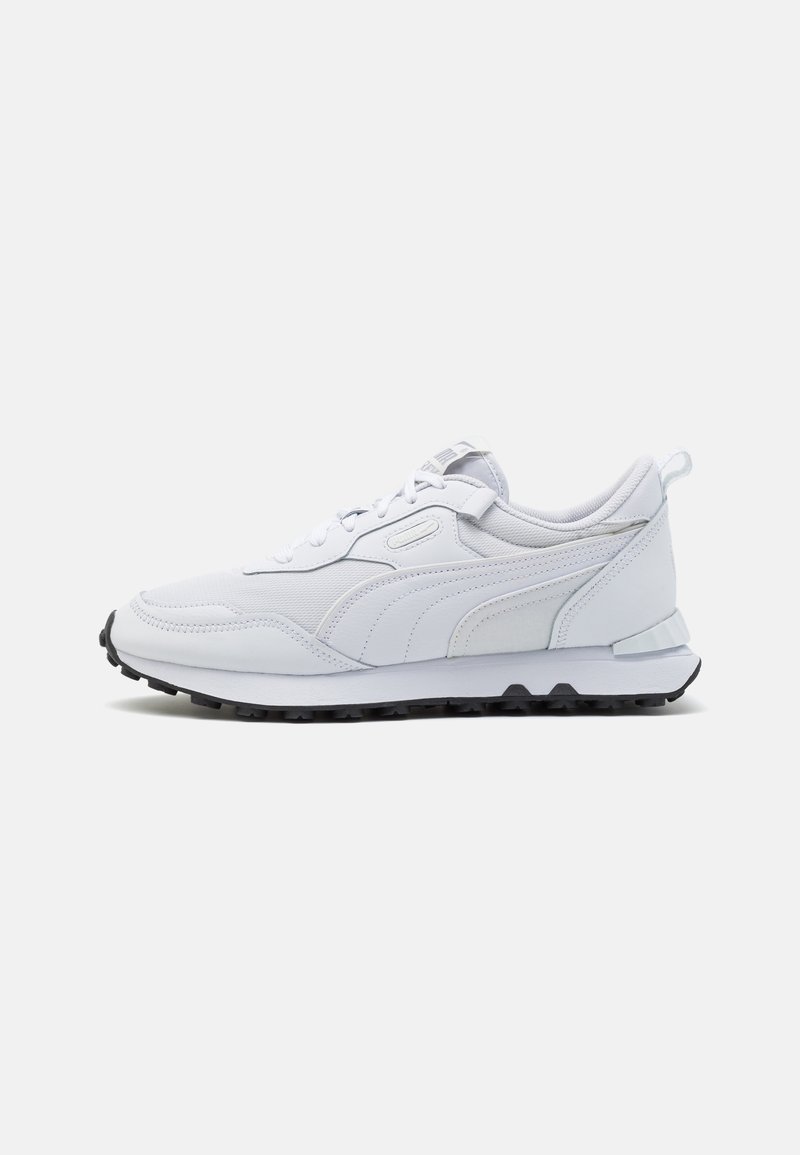 Baskets blanches de sport avec fermeture à lacets, dessus en mesh et cuir, semelle noire texturée sur fond clair uni.