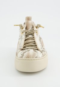 Zapatilla con estampado de serpiente en beige y blanco, suela gruesa, cordones beige atados en nudos y ojales dorados, mostrada desde una vista frontal sobre fondo blanco.