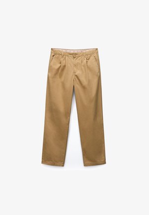 Proste spodnie w kolorze piaskowym z przednimi zakładkami, bocznymi kieszeniami, zapięciem na guzik i szlufkami na pasek na białym tle.