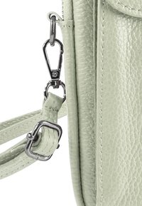 Lichtgroene handtas van getextureerd leer met zilverkleurige accessoires, een clipsluiting en een dun verstelbaar bandje. Duurzame stiknaden als accent.