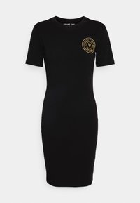 Svart figurnära klänning med korta ärmar, rund halsringning och en guld cirkulär Versace Jeans-logotyp på vänster bröst. Slät textur.