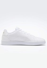 Baskets blanches avec empeigne synthétique lisse, fermeture à lacets, détails discrets de coutures, et semelle en caoutchouc solide. Logo de la marque sur la languette.