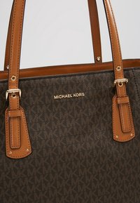 Sac cabas marron Michael Kors avec motif monogramme MK signature et anses en cuir camel avec détails de boucle dorée.