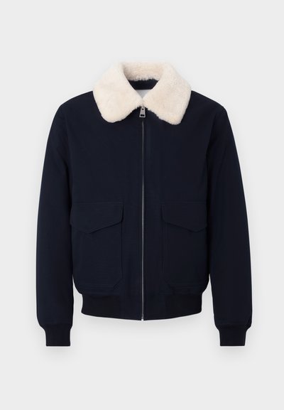 Mornarsko modra pilotka jakna z okroglim ovratnikom iz kremastega umetnega ovčjega krzna; ima zadrgo in dva sprednja žepa; rebrasti robovi na manšetah in spodnjem robu.