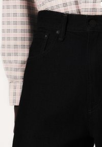 Jeans din denim de culoare blue închis, cu talie înaltă și un design minimalist. Prezintă cusături subtile și un închizător cu nasture pe față.
