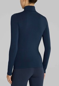 Maglia a maniche lunghe a collo alto di colore navy realizzata in tessuto liscio. Design aderente con colletto alto, spalle senza cuciture e silhouette snella.