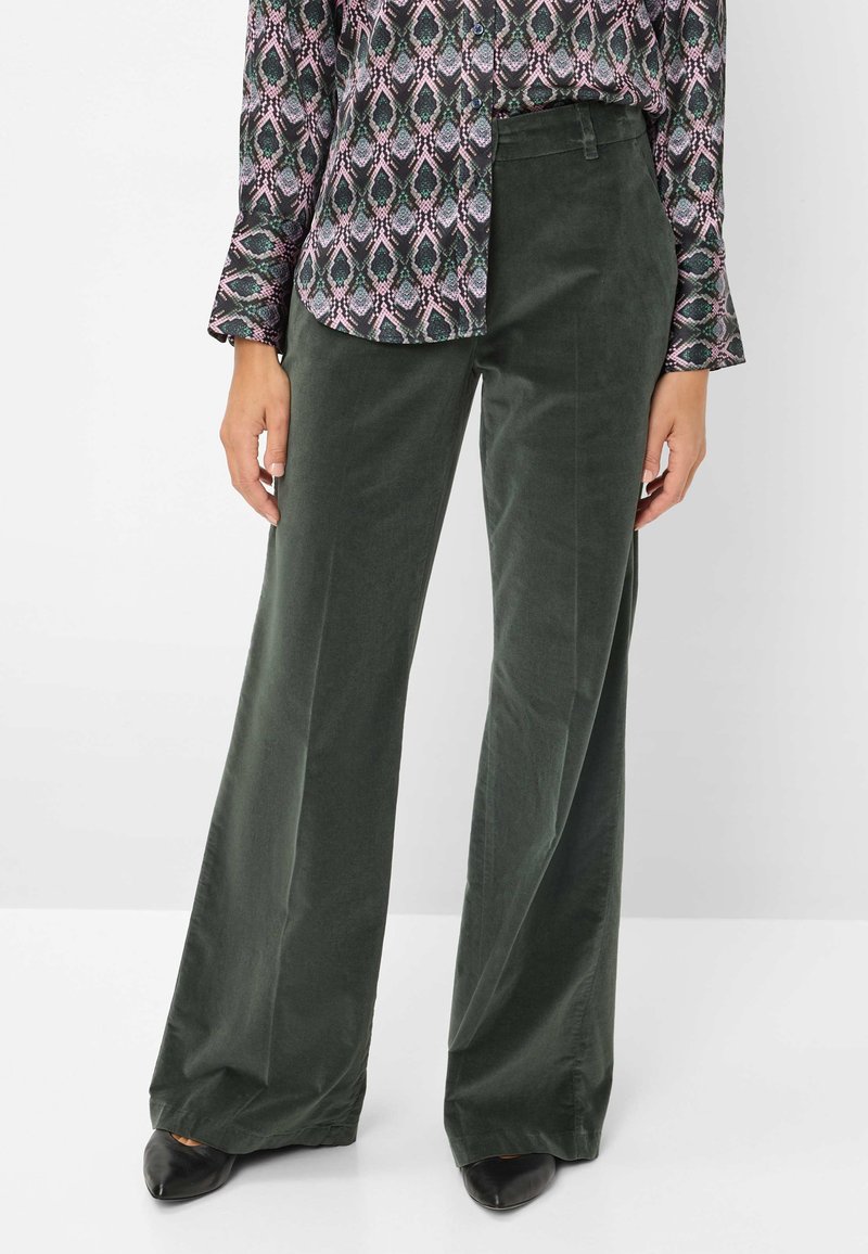 Pantalons en velours côtelé verts à jambes larges avec une texture lisse, dotés d'une taille cintrée et de poches latérales, associés à un haut à manches longues à motif.