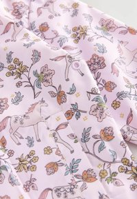 Light pink fabric with a pattern of unicorns, flowers, and leaves in pastel colors and a pink snap button closure.