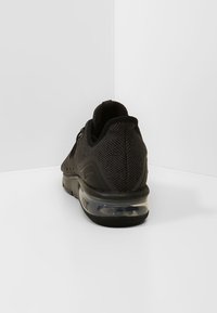 Czarne buty sportowe z teksturowaną, siateczkową cholewką, gumową podeszwą z przezroczystym systemem amortyzacji oraz subtelnym brandingiem z boku.