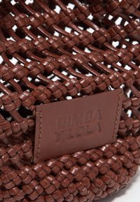 Bolso de mano de cuero marrón trenzado con un diseño texturizado y una placa de cuero con la marca y letras en relieve.