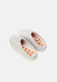 Λευκά παπούτσια χωρίς κορδόνια με υφή στην επιφάνεια και φαρδιές ανοίγματα. Η εσωτερική πλευρά έχει πορτοκαλί πουά σε λευκό φόντο, με το λογότυπο "Τμήμα Επ ιστήμης Νου".