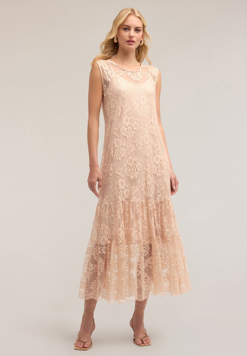 Lange kanten jurk in zachte blush, met ingewikkelde bloemenpatronen, korte mouwen en een gelaagde rand. Zachte textuur met een vloeiende silhoutte.