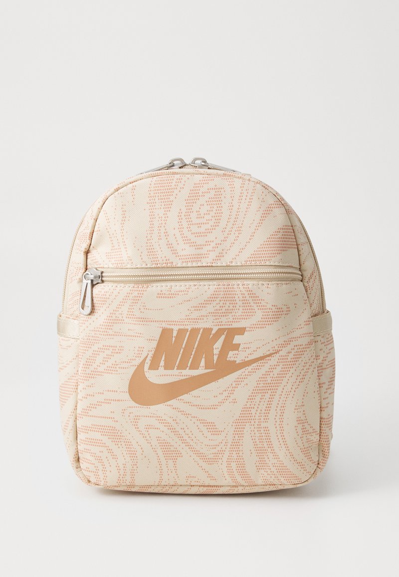 Šviesiai rožinis tekstūruotas kuprinės dizainas, su ryškiu auksiniu Nike logotipu ir priekiniais užtrauktukais.