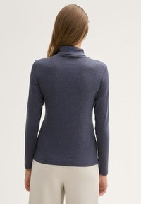 Haut à manches longues bleu marine avec un col haut, en tissu doux, au design ajusté et à la texture lisse, sans motifs ni accents visibles.