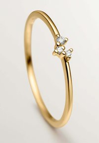 Anillo de oro con una banda delgada y lisa que presenta tres pequeños diamantes redondos agrupados en la parte superior, diseñado de manera minimalista.