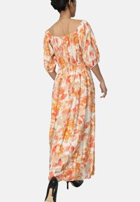 Robe maxi florale en crème, avec des motifs orange et rose, des manches bouffantes courtes et une taille élastique pour un ajustement décontracté.