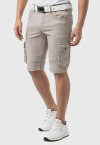 Beige gestreepte cargoshorts met meerdere zakken, gemaakt van stof met een gestructureerd oppervlak. Gepaard met witte sportsneakers.