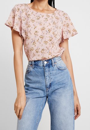Rosa Bluse mit kurzen Ärmeln und floralem Muster; runder Ausschnitt; kombiniert mit hochtaillierten blauen Denim-Jeans; lockere Passform.