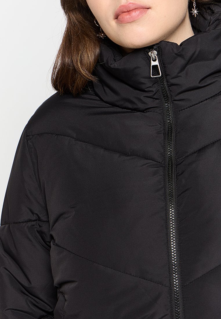 Giacca a piuma nera con colletto alto, dotata di zip frontale e motivo a zig-zag per una maggiore texture. Finitura esterna liscia.
