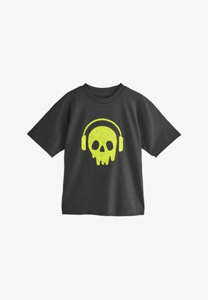 Tricou negru din bumbac, cu un grafic care luminează în întuneric reprezentând un craniu cu căști în galben aprins. Design cu mâneci scurte și guler rotund.