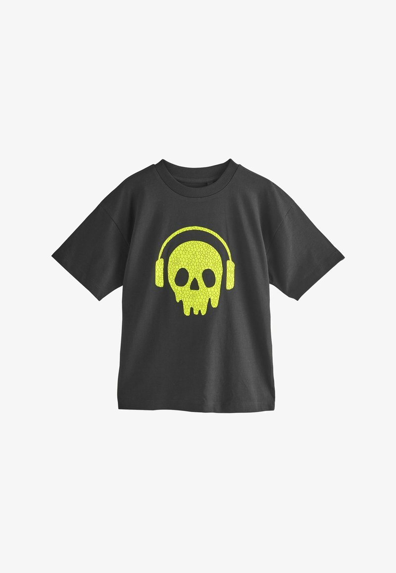 Fekete pamut póló, világító koponya grafikával, amely fülhallgatót visel élénk sárgában. Rövid ujjú és kerek nyakú fazon.